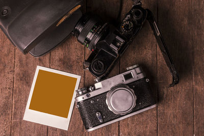 Directly above shot of cameras with blank instant transfer print on table