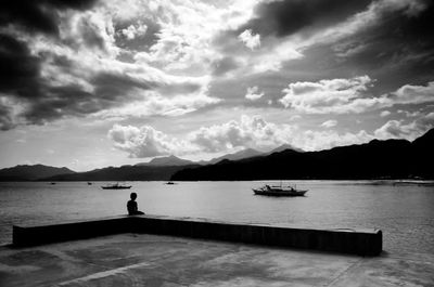 Scenic view of lake and mountains against cloudy sky