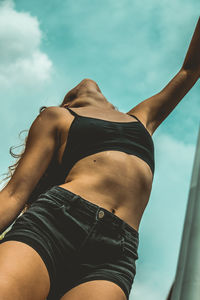 Midsection of young woman against sky