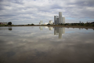 Scenic view of lake by buildings against sky