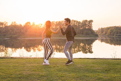 People standing by lake against sky