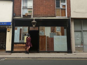 Woman walking on footpath by building