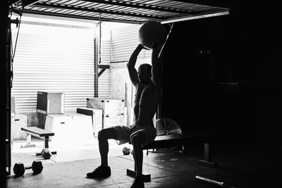 Fit young man working out with a ball and dumbells in a garage