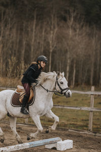 View of girl horseback riding