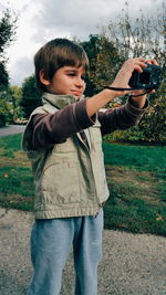 Boy photographing from camera at park