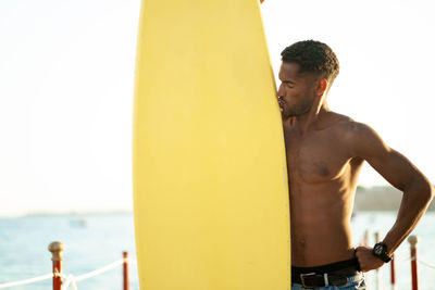 Rear view of shirtless man standing against sea