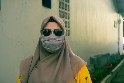 Portrait of man wearing sunglasses standing against city