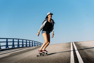 Woman skateboarding against blue sky