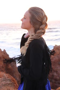 Side view of young woman standing at beach