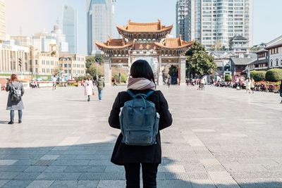 Full length rear view of woman standing in city