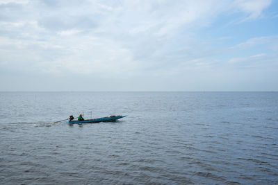 Man sitting on boat in sea against sky