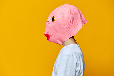 Portrait of woman wearing mask against yellow background