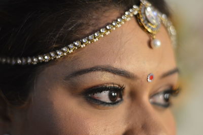 Cropped image of bride with make up and jewelry looking away
