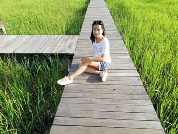 Full length portrait of woman sitting on boardwalk