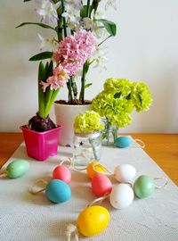 Colorful easter eggs with flowers in vases on table