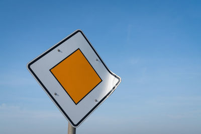 Low angle view of road sign against blue sky