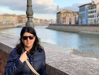 Portrait of mature woman wearing sunglasses by canal in city