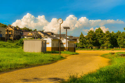 Houses on field by trees against sky