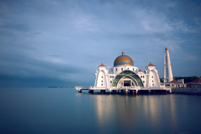 View of building by water against sky