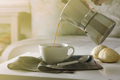 Close-up of person pouring coffee in cup on table