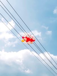 Low angle view of telephone pole against sky with balloons 