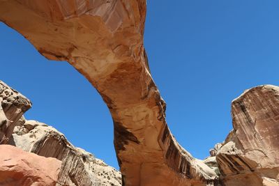 Looking up at a large stone bridge or arch and blue sky in utah
