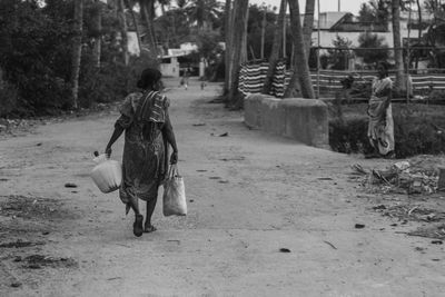 Rear view of senior man walking on dirt road