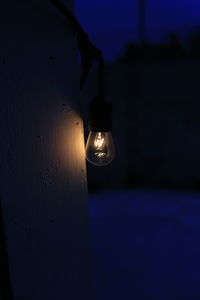 Close-up of illuminated light bulb against sky at night