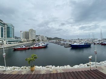 Boats moored in harbor against buildings in city