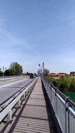 Surface level of footbridge against blue sky