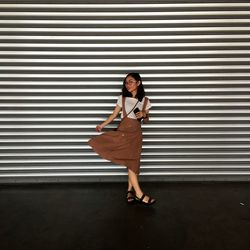 Full length of young woman standing against closed shutter