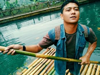 Portrait of young man standing on wooden raft