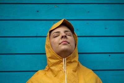 Woman in hood standing against wall