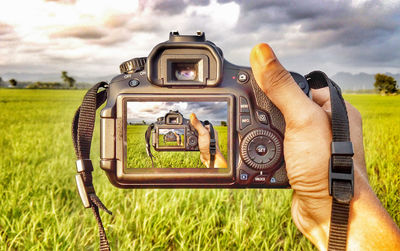 Man photographing camera on field against sky