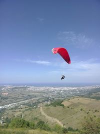 Man paragliding over landscape in sky