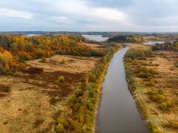 Aerial view on the river and various trees with orange, yellow and green leaves. cloudy sky. 