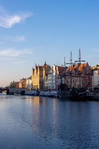 View of river by buildings in city against sky