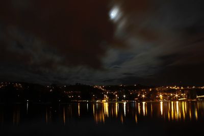 Reflection of illuminated buildings in calm sea at night