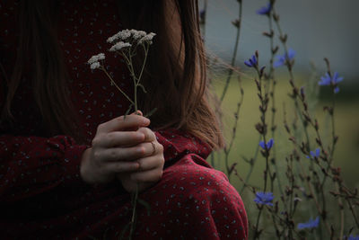 Midsection of woman holding flowering plant