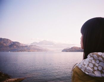 Rear view of woman by lake against clear sky