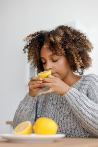 Portrait of young woman holding orange fruit against white background