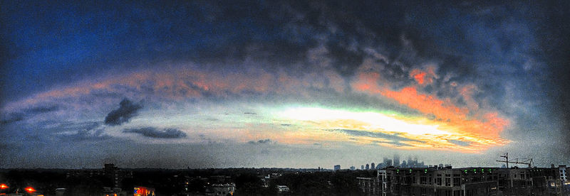 View of illuminated cityscape against cloudy sky at sunset