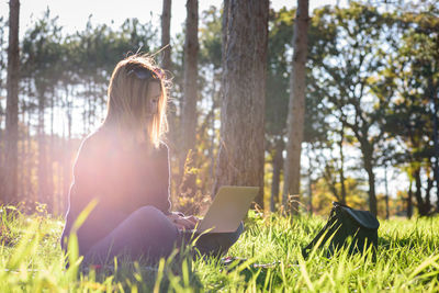 Young woman using phone while sitting on grass