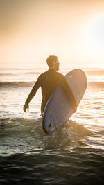 Full length of man on beach against sky during sunset