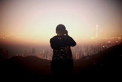 Woman photographing illuminated cityscape at night