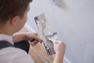 Man removes holes and bumps on the wall with a spatula and plaster