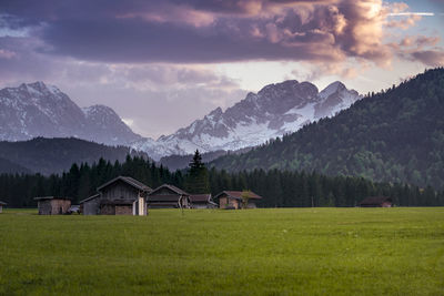 House on field by mountains against sky
