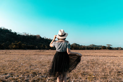 Rear view of woman standing on field against clear sky