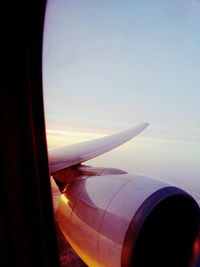 Close-up of airplane wing against sky during sunset