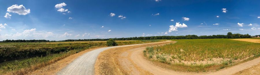 Panoramic shot of dirt road along countryside landscape